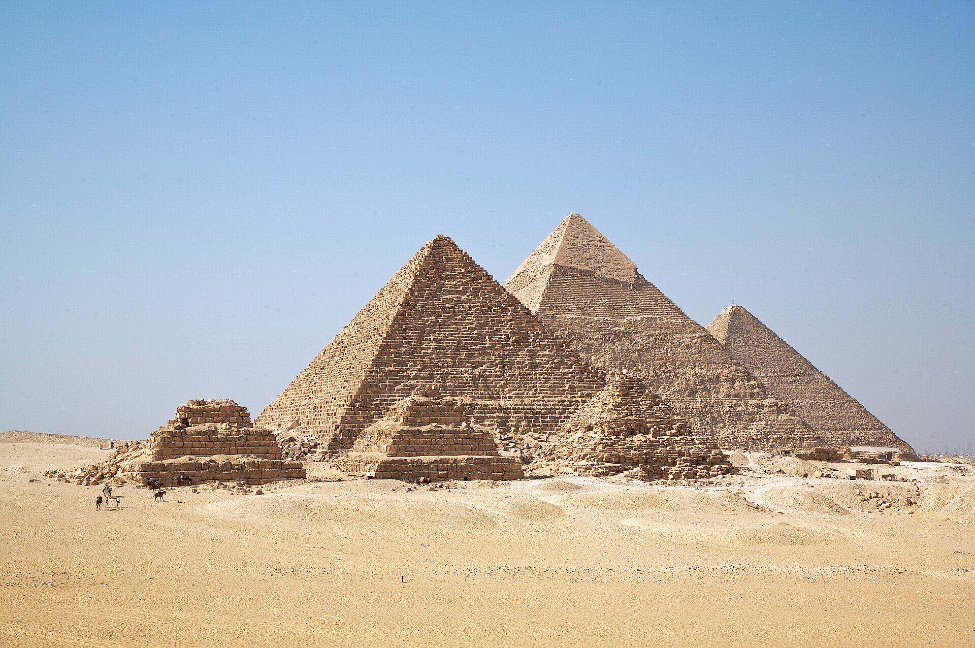 Aerial view of the Great Pyramids of Giza at sunrise, showing all three main pyramid structures and the surrounding desert plateau